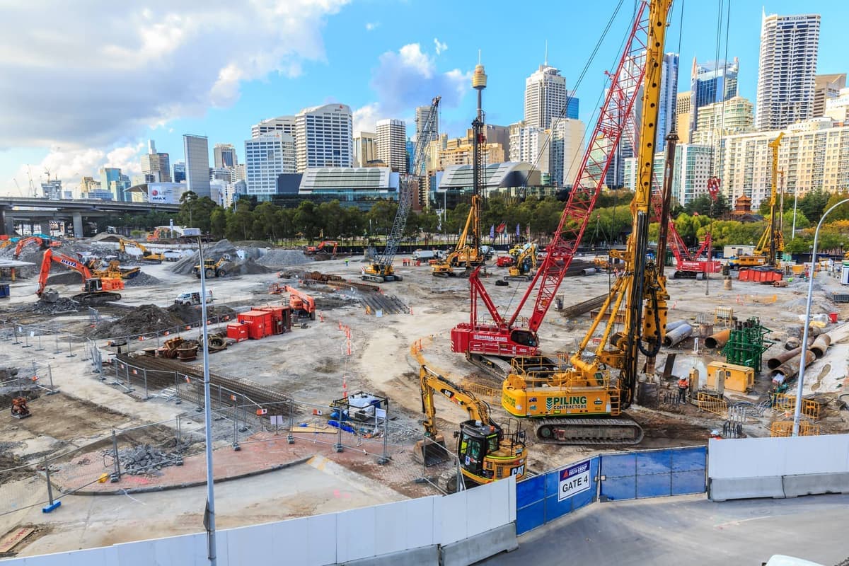 Aerial view of a construction site with cranes and Sydney skyline