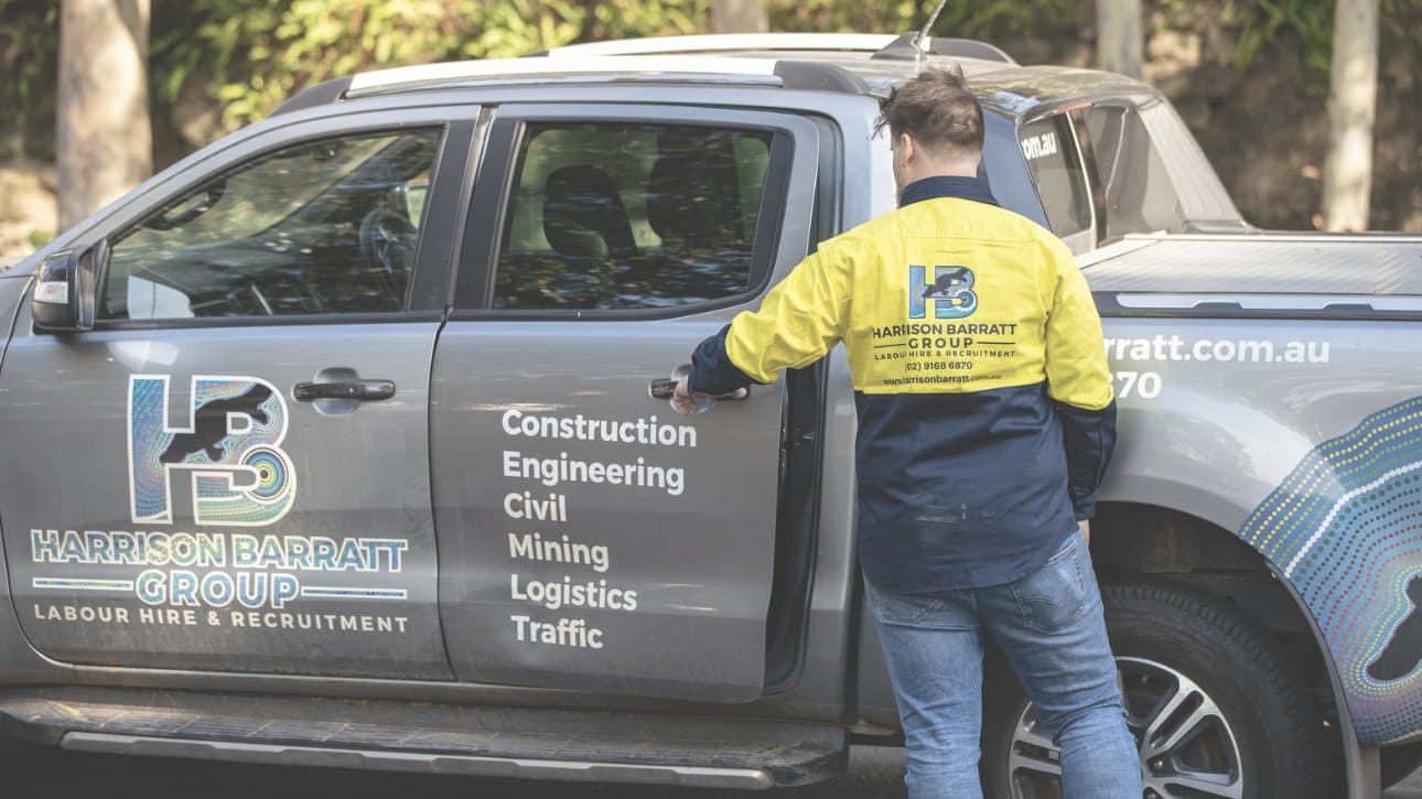 HBG recruiter in hi-vis jacket next to branded ute